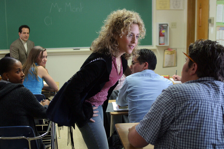 Bitty Schram as Sharona Fleming addressing a student sitting at a desk in a classroom
