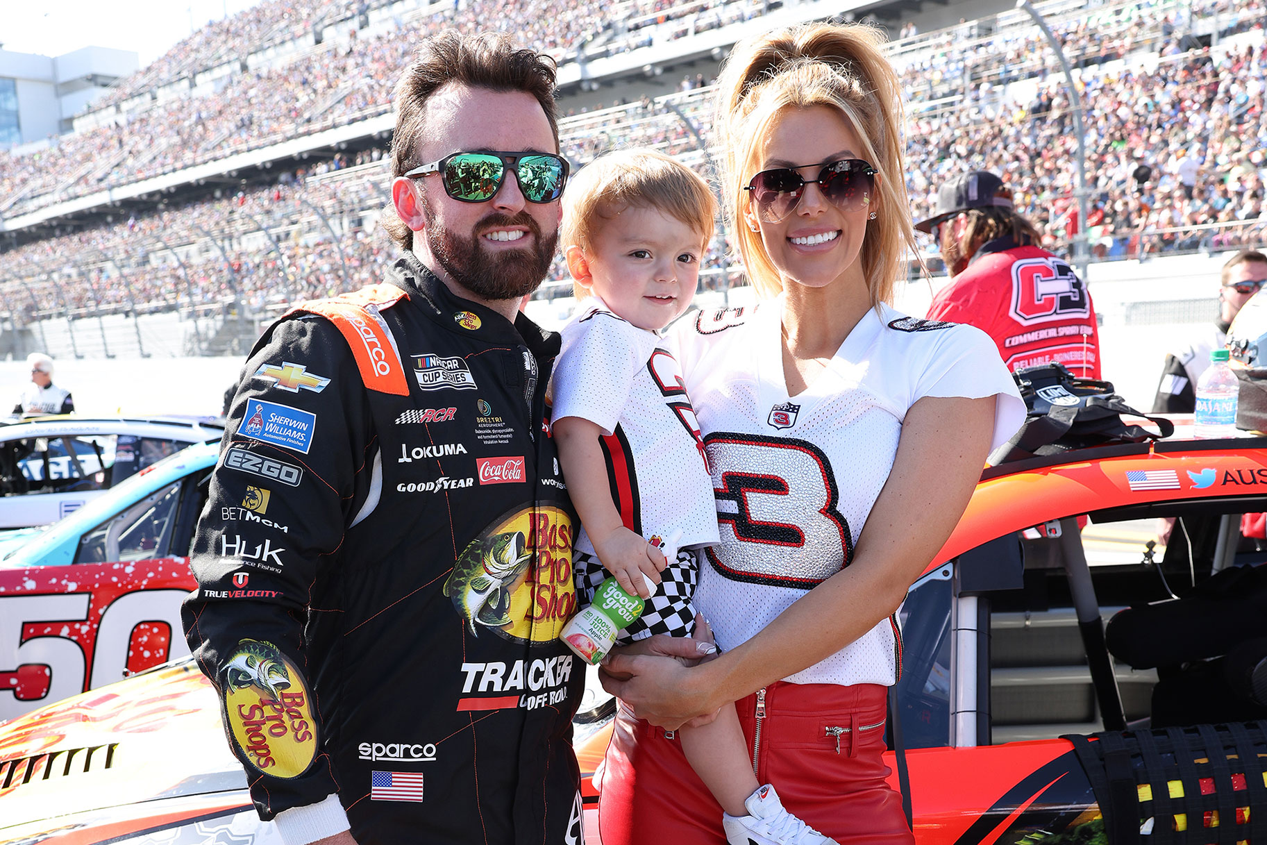 Austin Dillon with his wife and child, posing at a nascar event