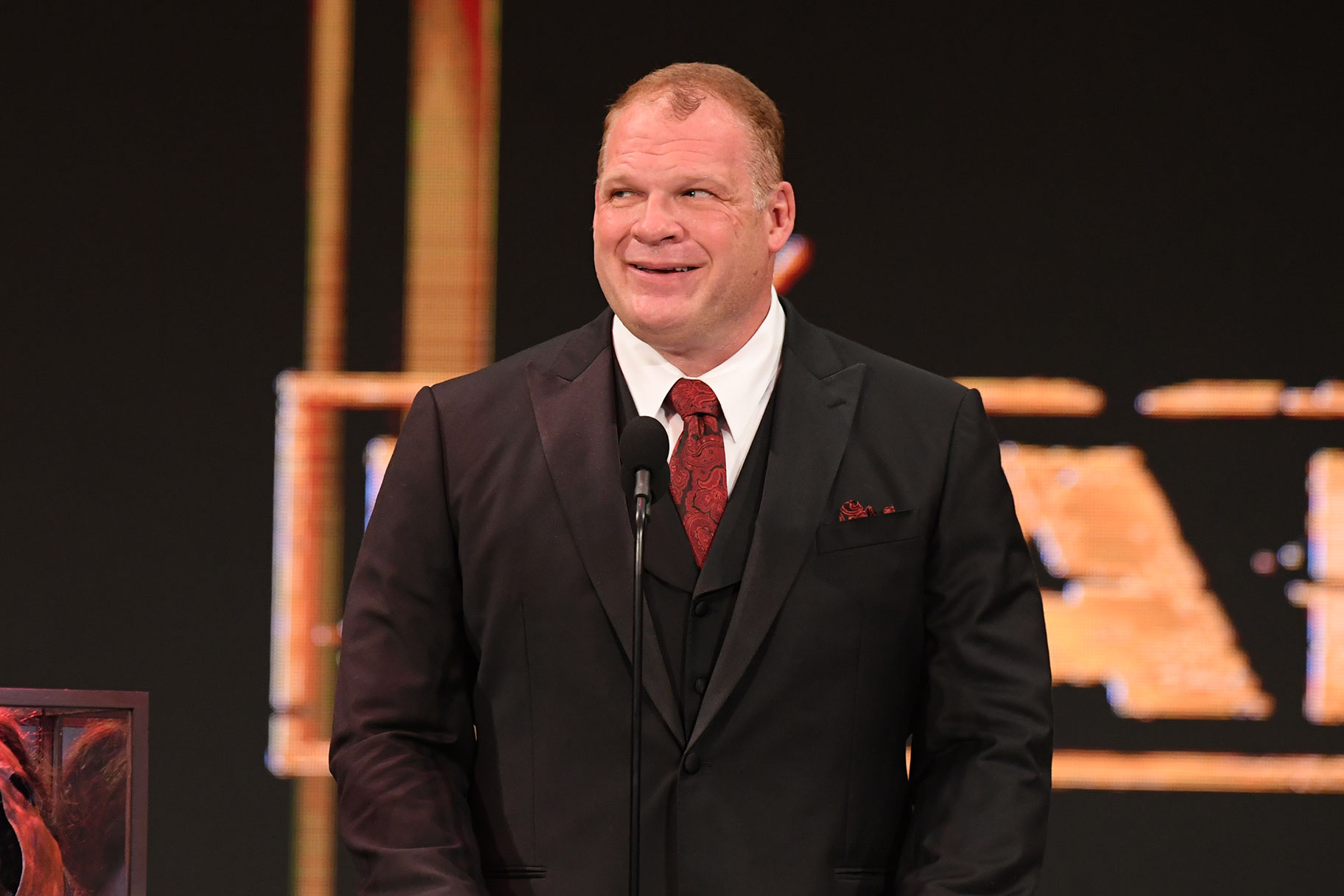 Kane wearing a suit and smiling on stage