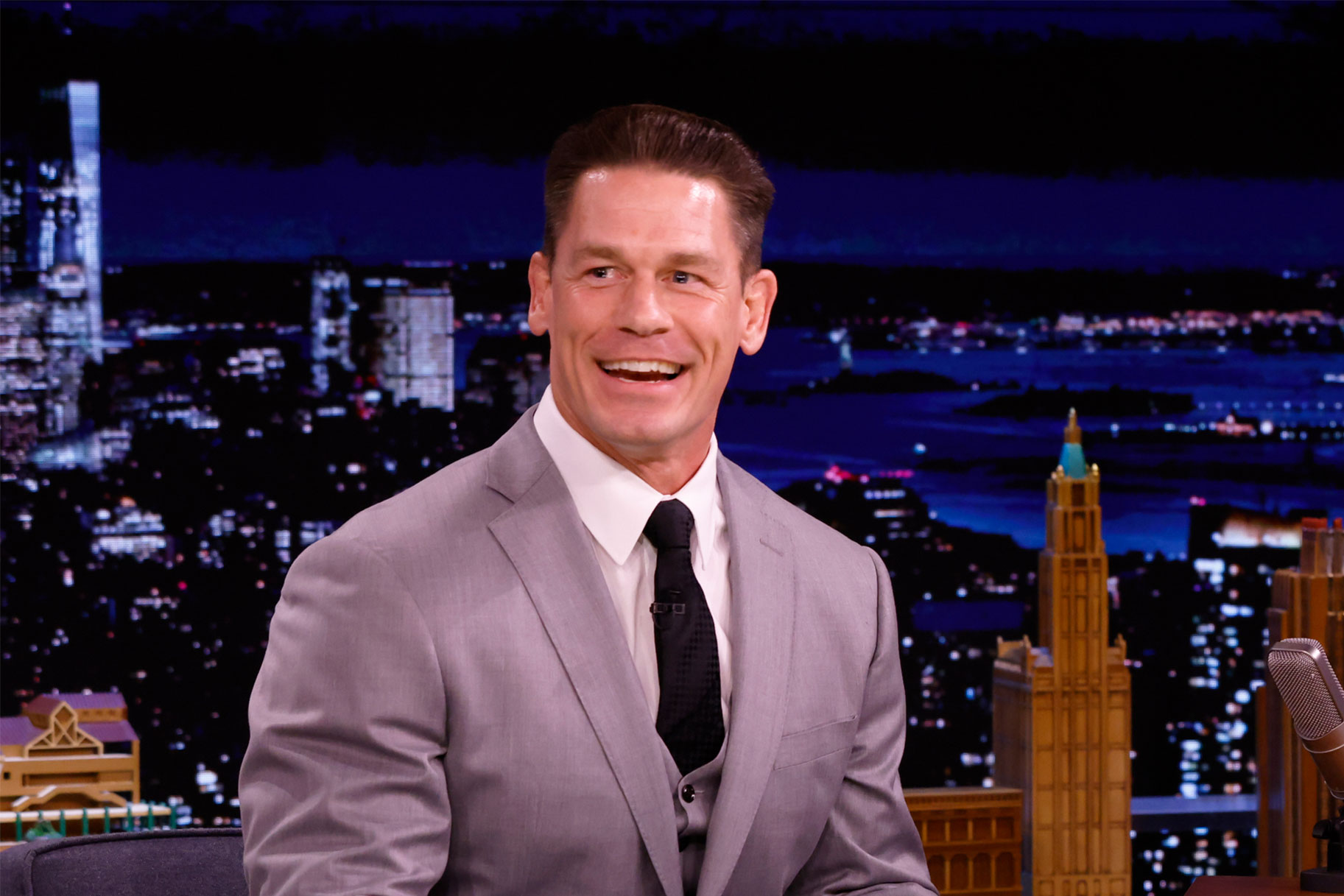 John Cena smiling while wearing a gray suit