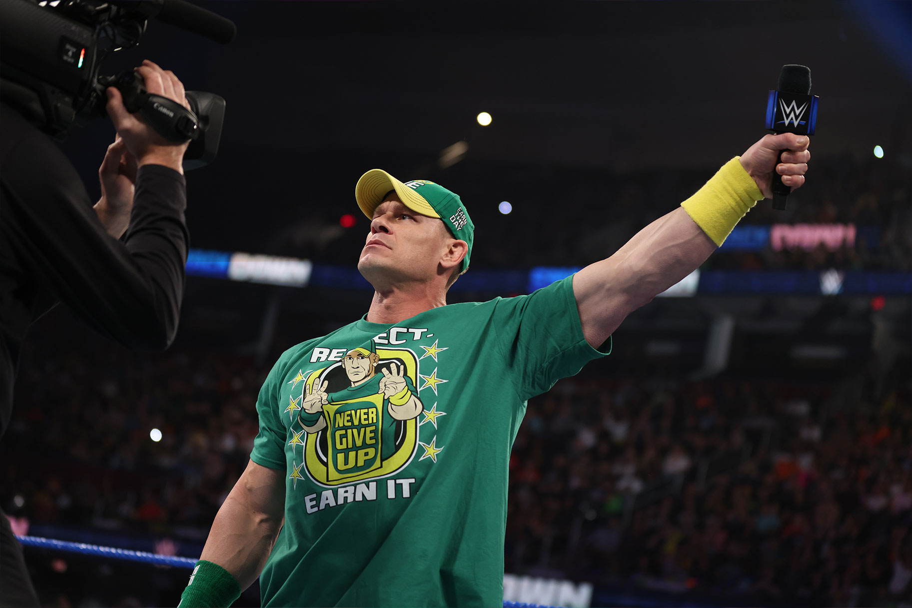 John Cena holding a mic out to the crowd while standing in the ring