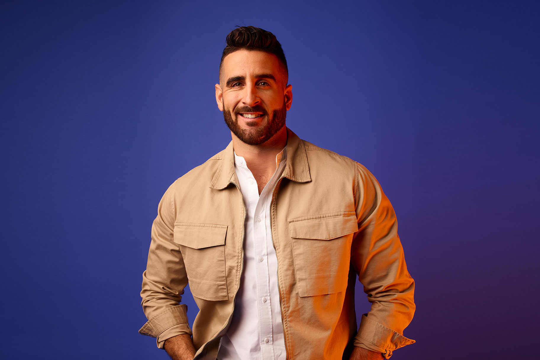 Paul Swan smiling while standing in front of a dark blue backdrop