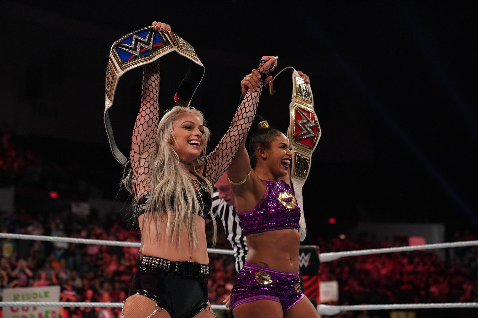 Liv Morgan and Bianca Belair lifting their belts into the air