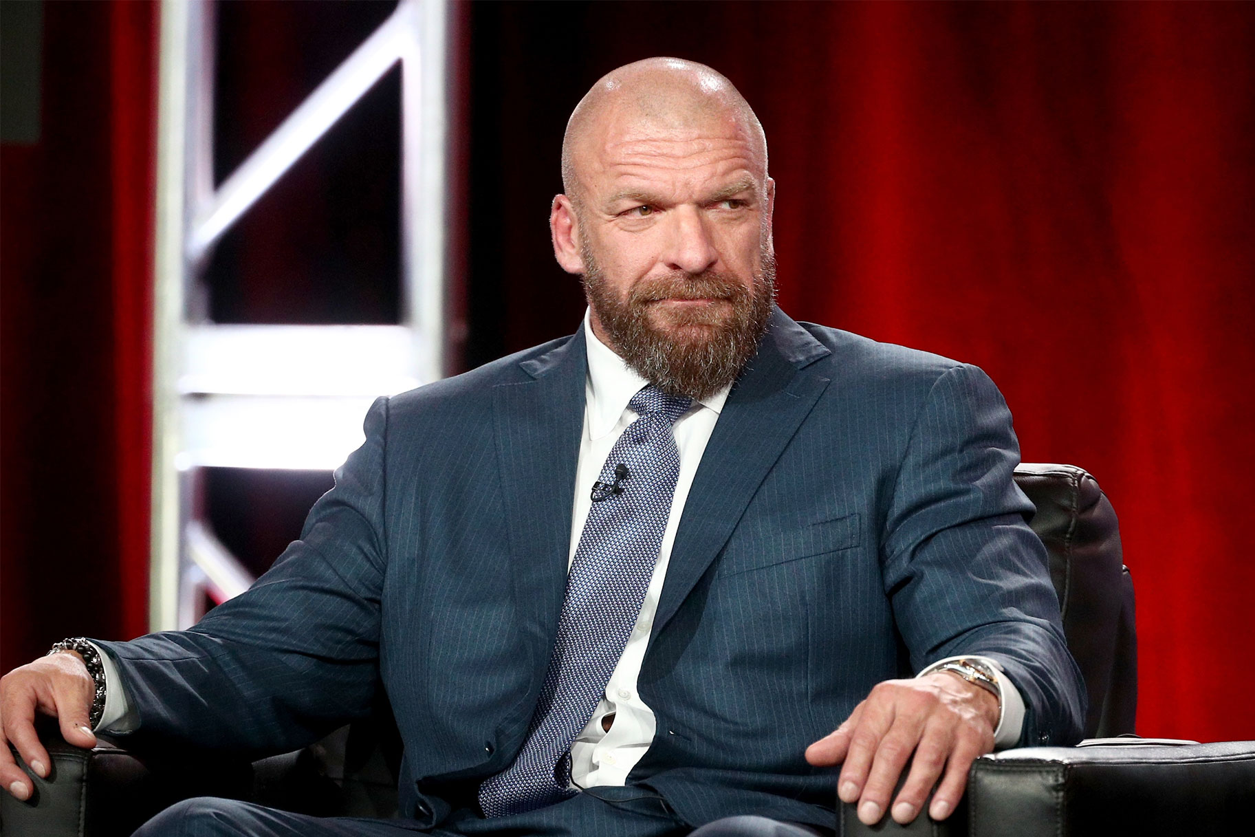 Triple H sitting in a chair, wearing a suit