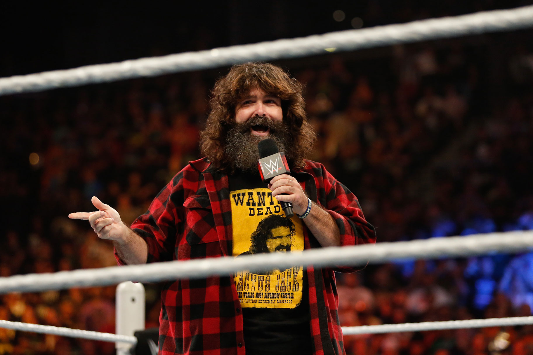 Mick Foley speaking into a mic inside the ring