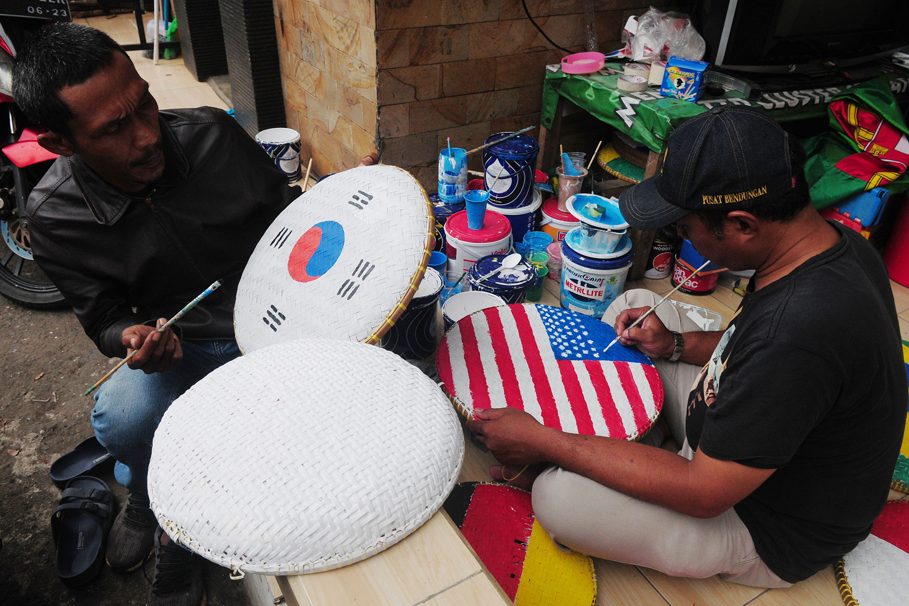 Locals paint flags of World Cup teams at the Maharaja Cluster Cemara Housing