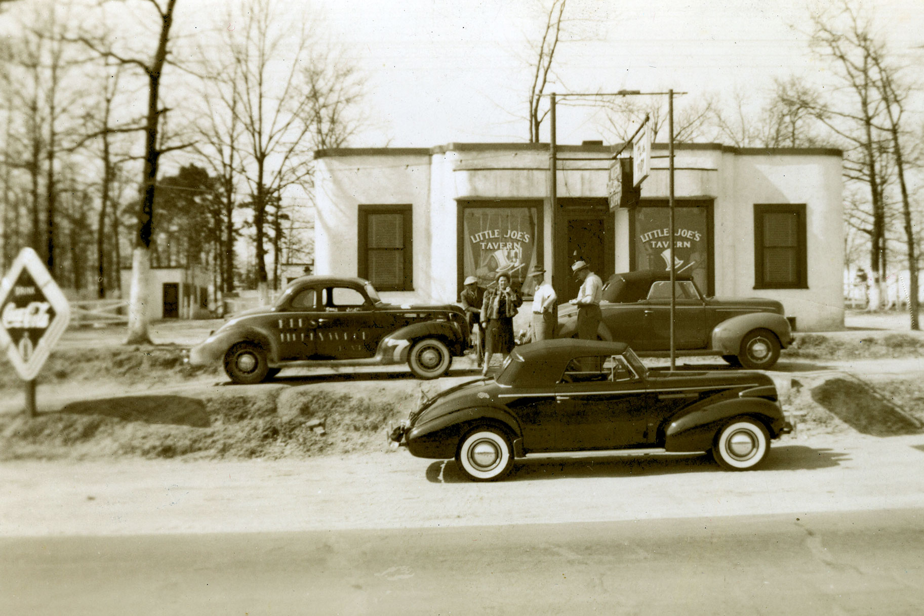 Late-1930s: Many of stock car racing’s early stars learned their driving trade as “bootleggers” hauling illegal liquor. Among them were Smokey Purser, Lloyd Seay, Roy Hall and Joe Littlejohn, whose racecar (No. 7) is seen outside the “Little Joe’s” tavern. Note how Littlejohn’s racer did not look much different than the street cars in the photo.