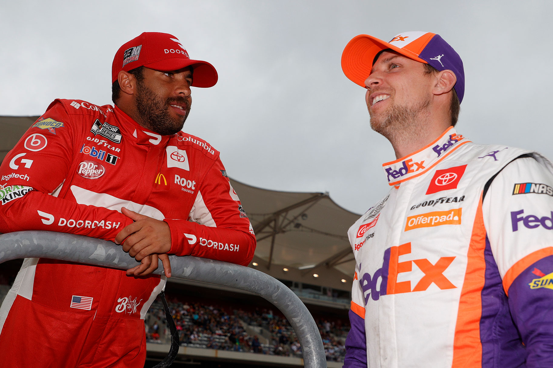 Bubba Wallace and Denny Hamlin smiling while speaking to one another