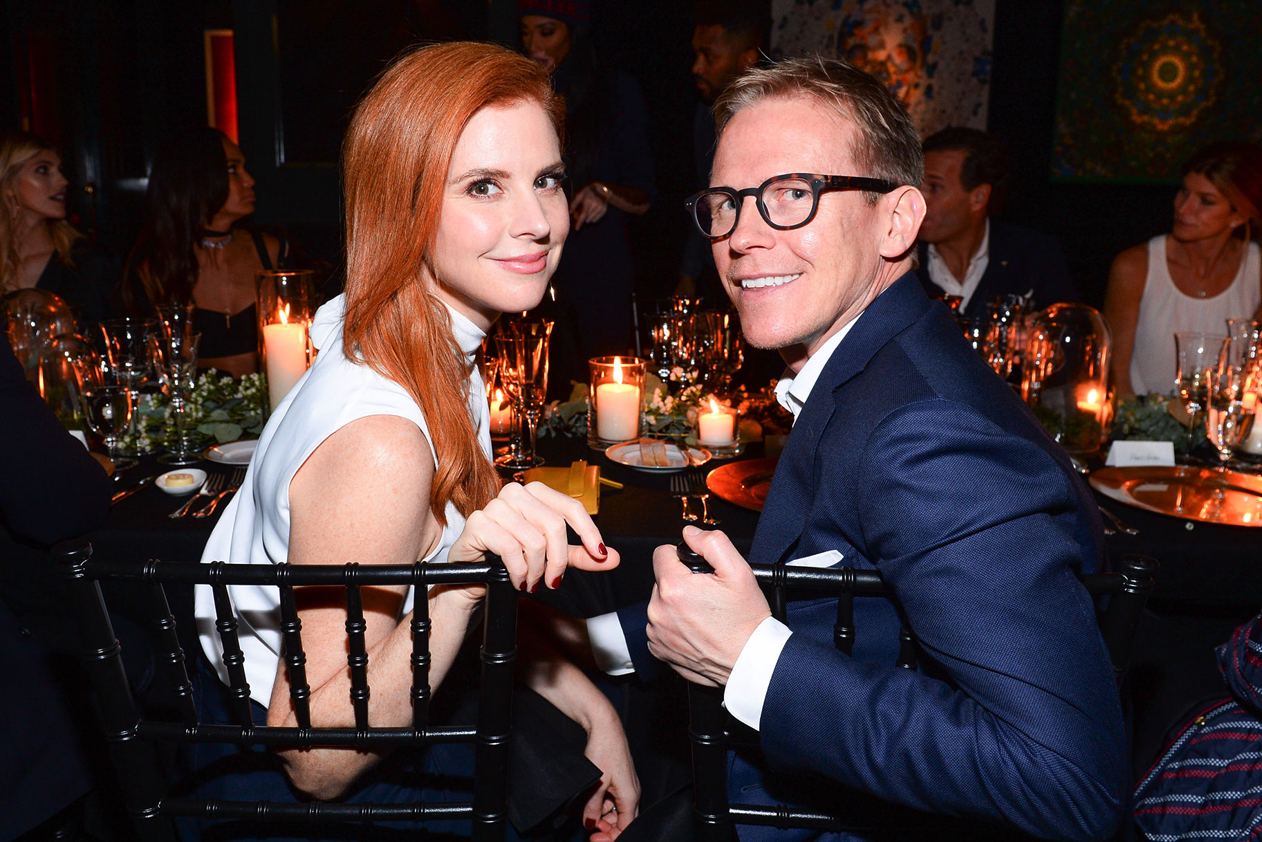 Sarah Rafferty and her Husband smile for a photo while seated at a dinner table