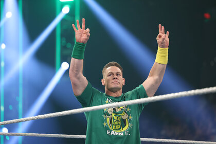 John Cena holding up three fingers on each hand while standing in the ring