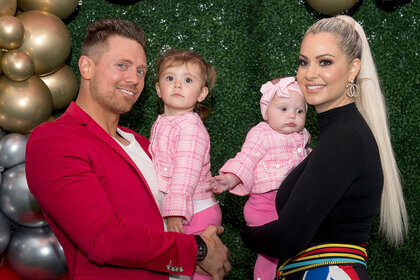 The Miz and Maryse holding their two daughters and smiling at the camera