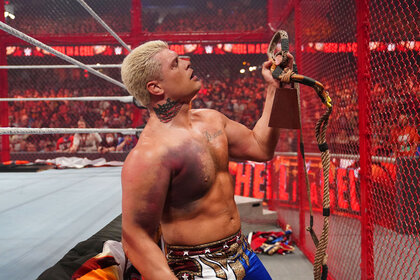 Cody Rhodes holding a mysterious object up while he stand outside the ring