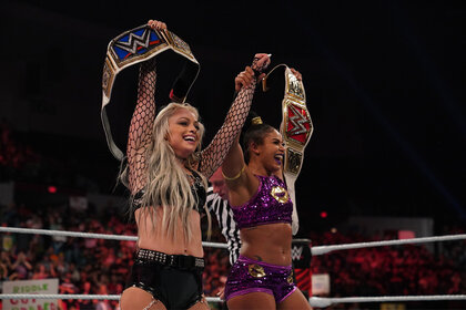 Liv Morgan and Bianca Belair lifting their belts into the air