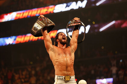 Seth Rollins at SummerSlam holding two belts up