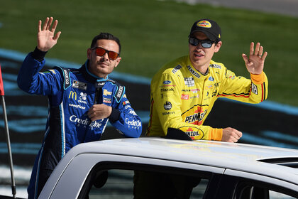 Logano and Larson waving to the crowd from the back of a pickup truck