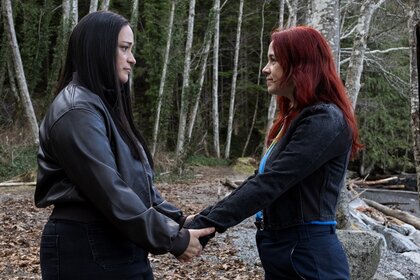 Asta Twelvetrees (Sara Tomko) and D'Arcy Bloom (Alice Wetterlund) hold hands in the woods on Resident Alien Episode 407.