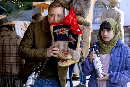 Harry Vanderspeigle (Alan Tudyk) holds embroidered boots next to Sahar (Gracelyn Awad Rinke) who holds 'manticide spray' on Resident Alien Episode 408.
