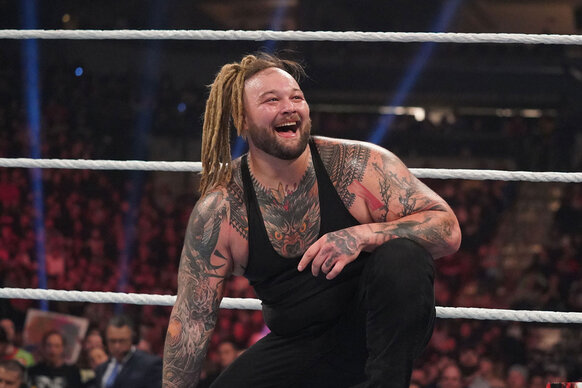 Bray Wyatt smiles at the crowd while kneeling in the ring