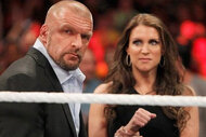 Stephanie McMahon standing behind Triple H, looking at him