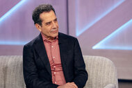 Tony Shalhoub sits on a couch on the set of The Kelly Clarkson Show