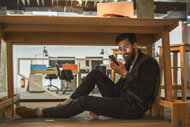 A Man sitting Under Table On his Phone