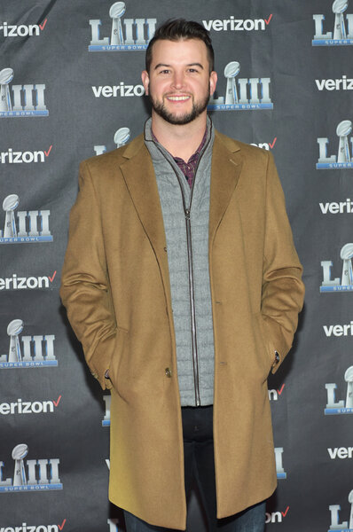 AJ McCarron wearing a brown overcoat at the arrivals carpet for "The Team That Wouldn't Be Here" documentary.