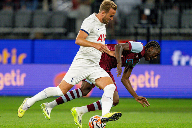 Harry Kane chases the ball while tripping an opponent on the field