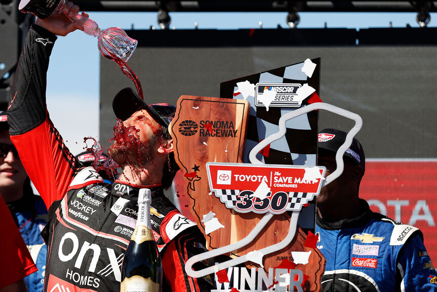 Daniel Suarez, driver of the Onx Homes/Renu Chevrolet, celebrates by pouring wine on himself in victory lane after winning the NASCAR Cup Series