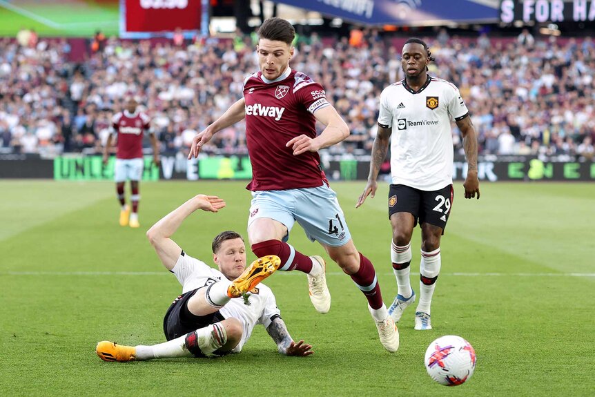 Wout Weghorst tackles Declan Rice for the ball on the field during a Premier League match