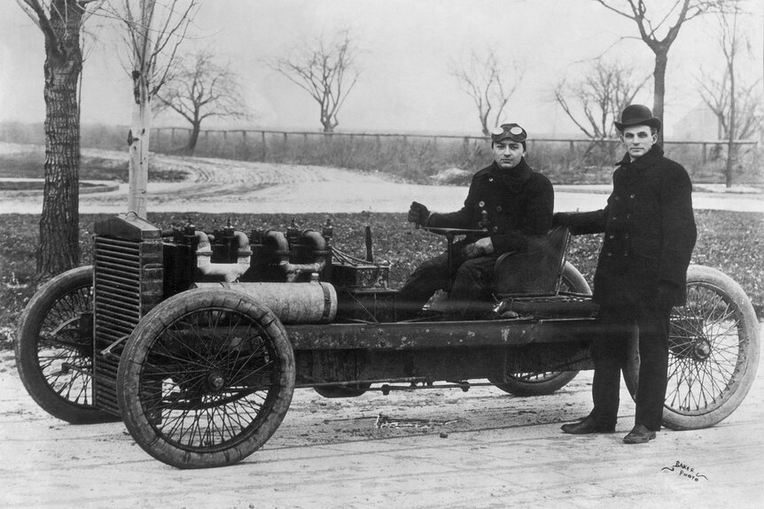 Henry Ford standing beside his famous racer 999 with Barney Oldfield at the tiller.