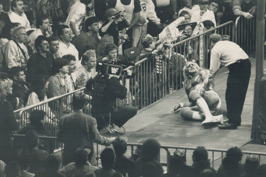 Hulk Hogan lay son the ground outside of the ring in this black and white photo