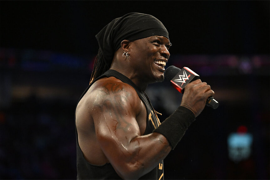 R Truth speaks into the mic while standing in the ring
