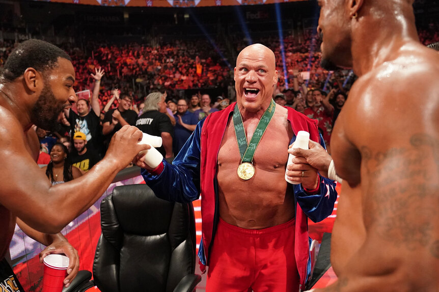 Kurt Angle and the Street Profits share a protein drink during a match
