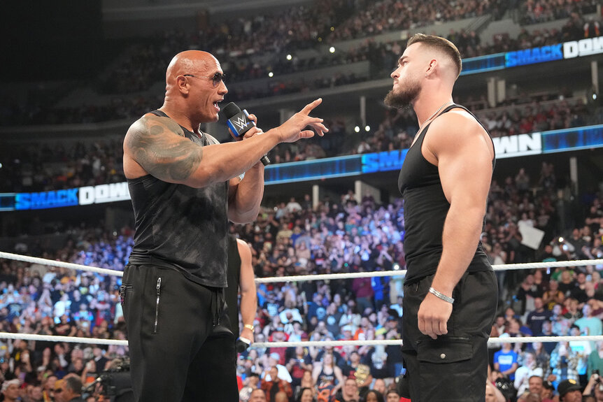 The Rock speaks to another wrestler in the ring
