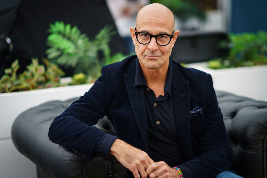 Stanley Tucci sitting and posing for a photo
