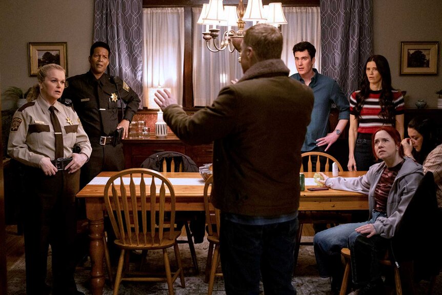 Resident Alien cast standing around a table